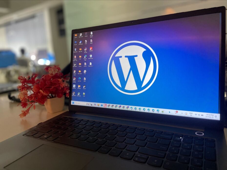 A laptop on a desk with a large WordPress logo displayed on the screen - free image from The WordPress Photo Directory